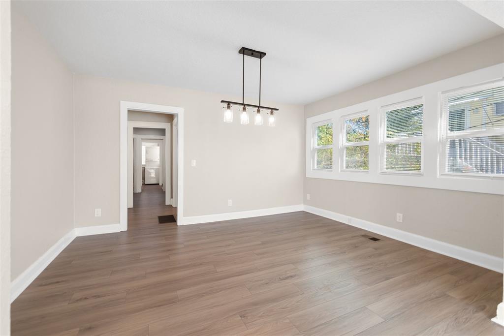 An empty dining room features light wood-look flooring, white trim, and a modern linear chandelier — 781 31ST AVENUE N, ST PETERSBURG, FL