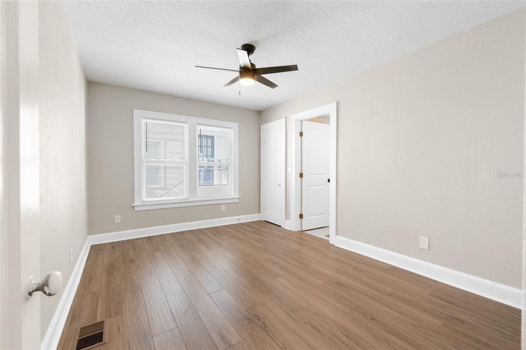 An empty bedroom features light-colored walls, wood-look flooring, a ceiling fan, and two doorways — 781 31ST AVENUE N, ST PETERSBURG, FL