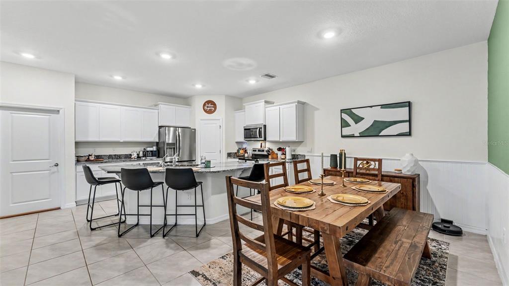 A kitchen with white cabinets and a granite island flows into a dining area — 3817 STORMY THISTLE PLACE, PLANT CITY, FL