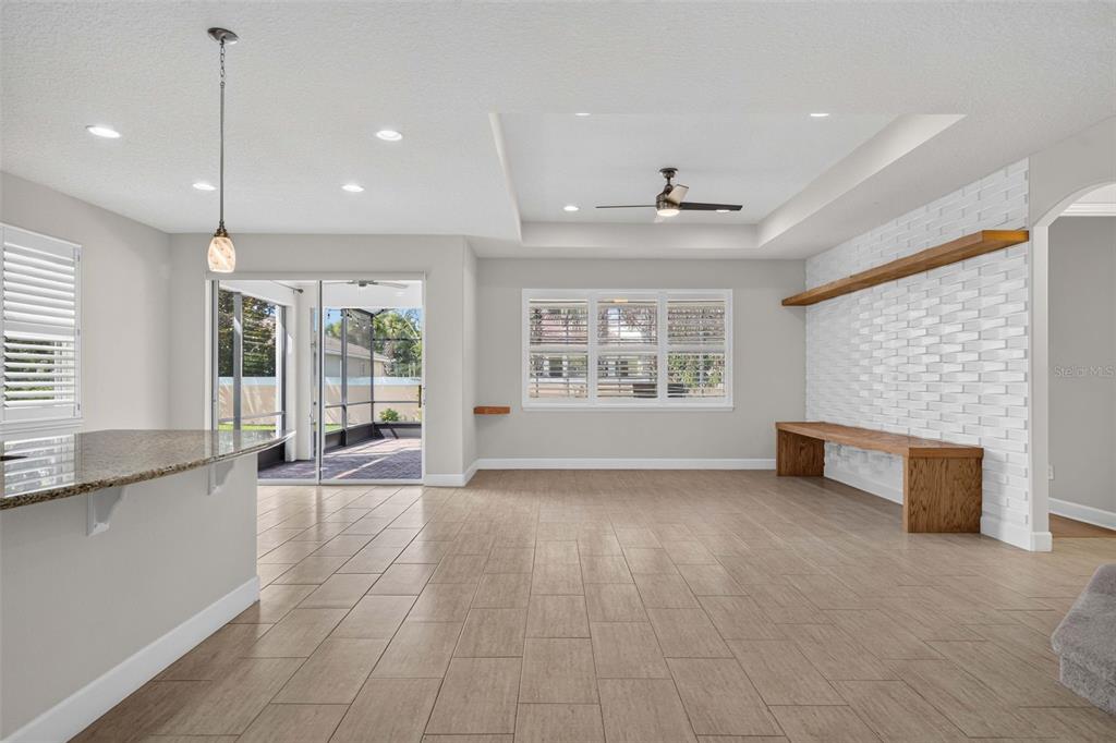 A living room features light tile floors, a white brick accent wall, and wood shelving — 11812 PADUA LANE, ORLANDO, FL