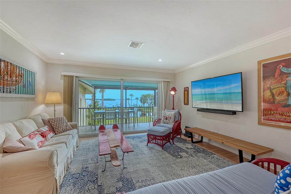 A living room features a white sofa, a television, and sliding doors opening to a balcony — 4234 GULF OF MEXICO DRIVE UNIT E2, LONGBOAT KEY, FL
