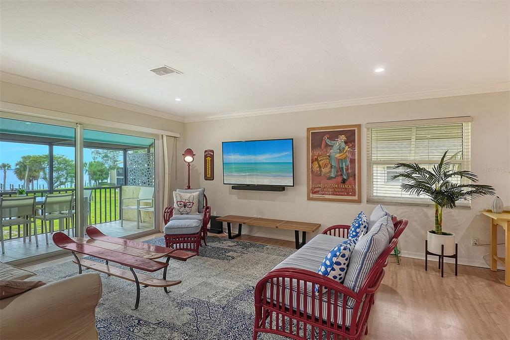 A living room features a television, a red wicker sofa, and a sliding glass door — 4234 GULF OF MEXICO DRIVE UNIT E2, LONGBOAT KEY, FL