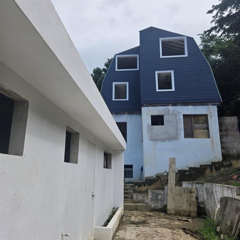 A multi-story house with blue siding and a white concrete structure stands outdoors — 9966 CARRETERA, RIO GRANDE, PR