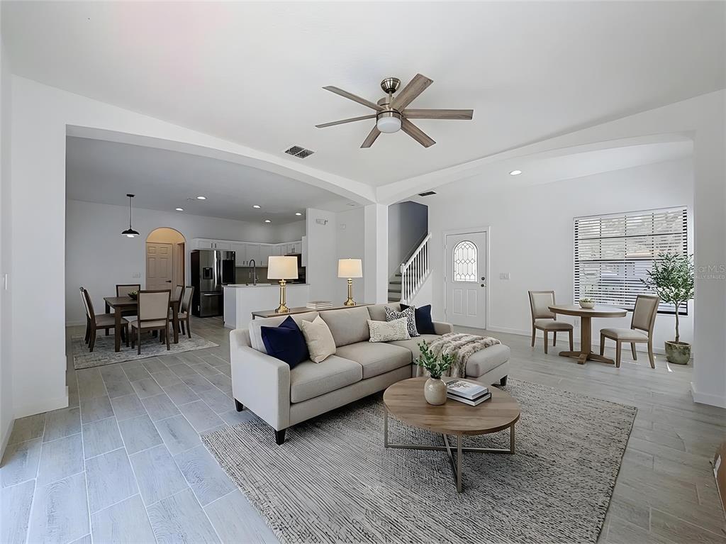 An open-concept living room and dining area features light tile flooring and a ceiling fan — 16710 CARIBBEAN BREEZE WAY, CLERMONT, FL