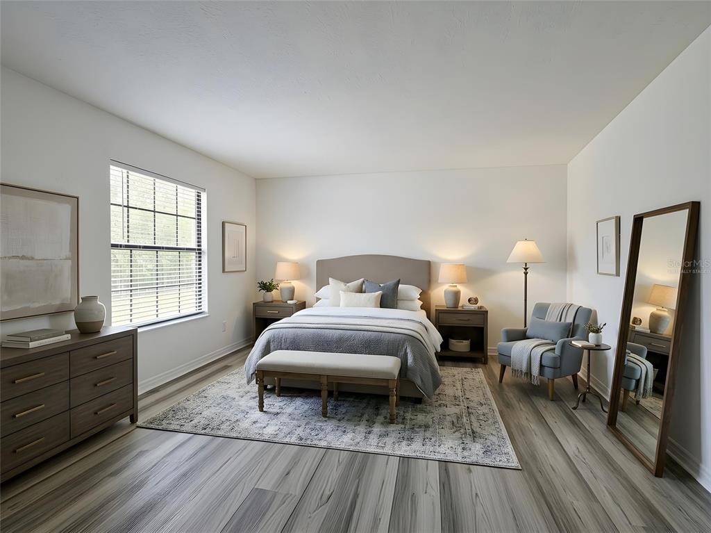 A bedroom features a bed, dresser, armchair, floor mirror, and wood-look flooring — 16710 CARIBBEAN BREEZE WAY, CLERMONT, FL