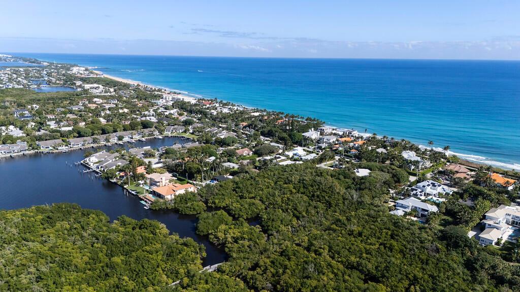 An aerial view shows coastal homes nestled among dense trees along a canal and beach — 6064 N Ocean Boulevard, Ocean Ridge FL 33435, OCEAN RIDGE, FL