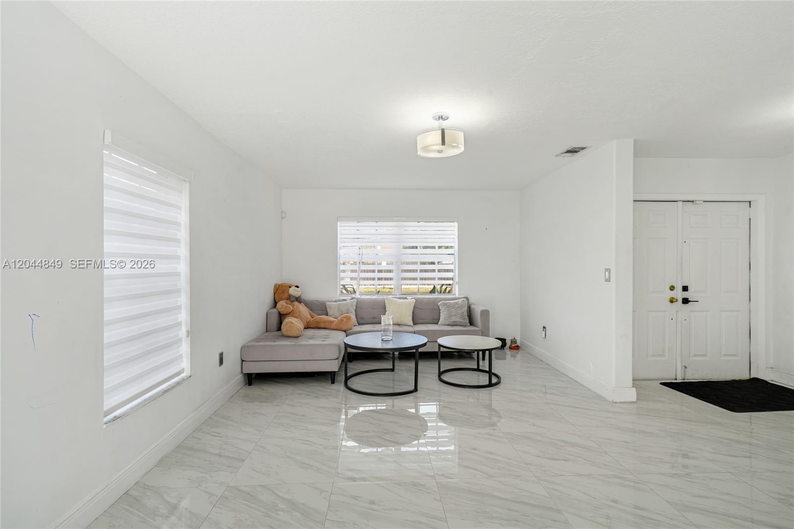 A living room features white walls, marble-look tile flooring, a gray sectional sofa, and two coffee tables — 16546 SW 103rd Ln, Miami FL 33196, MIAMI, FL