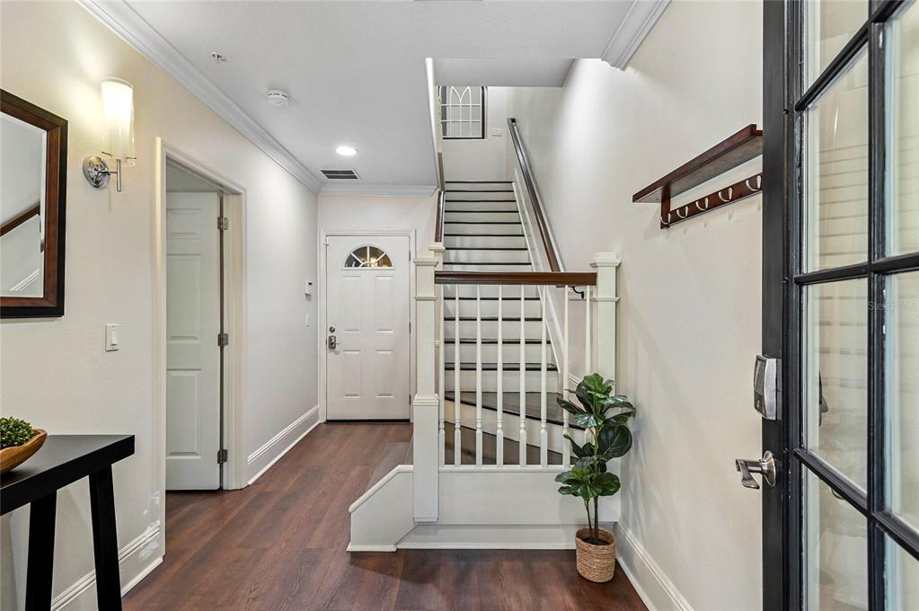 An entryway features dark wood flooring, a staircase with white railings, and a front door — 1659 COMMON WAY ROAD, ORLANDO, FL