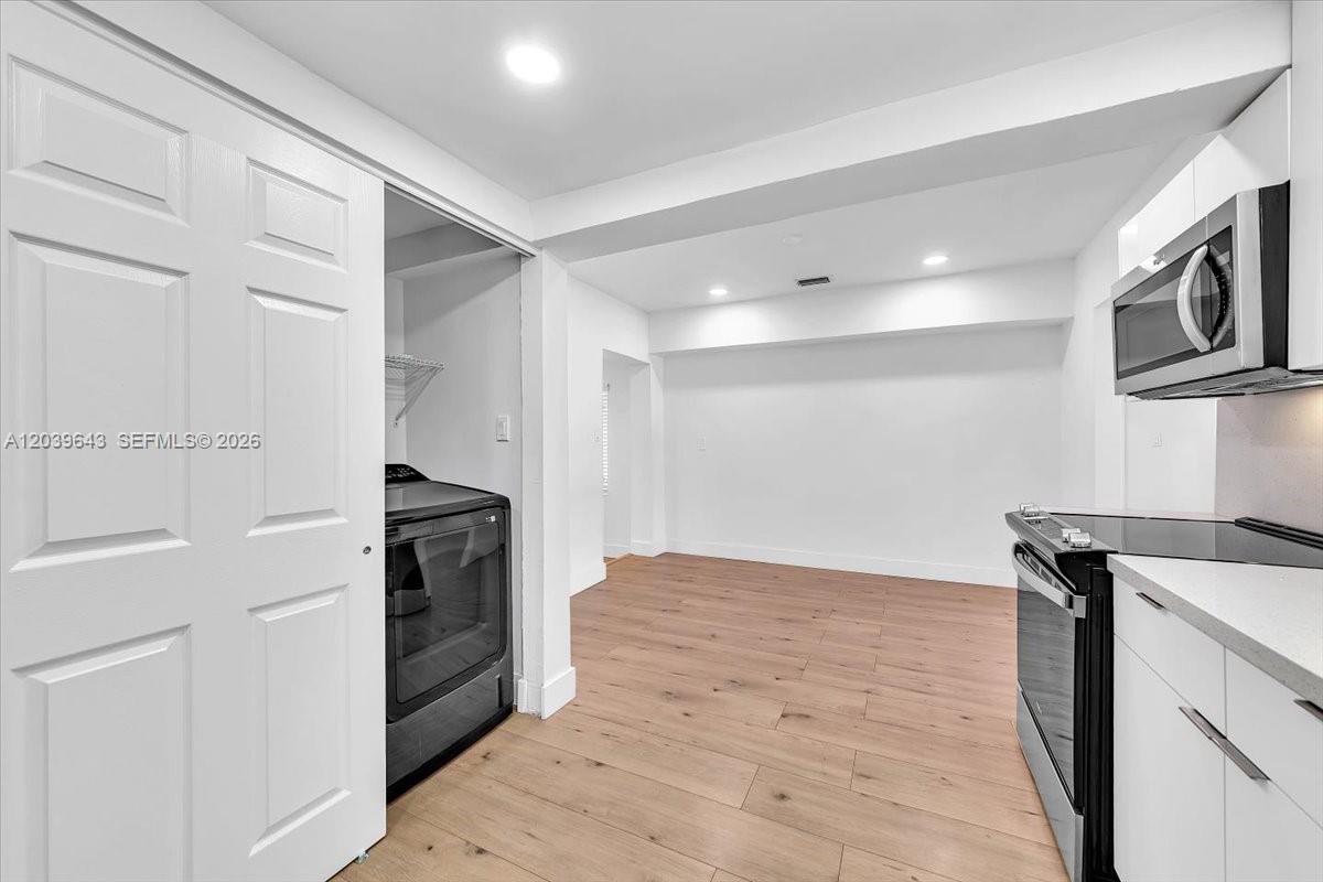 A kitchen area features white cabinets, stainless steel appliances, and light wood-look flooring — 4719 E 8th Ct, Hialeah FL 33013, HIALEAH, FL