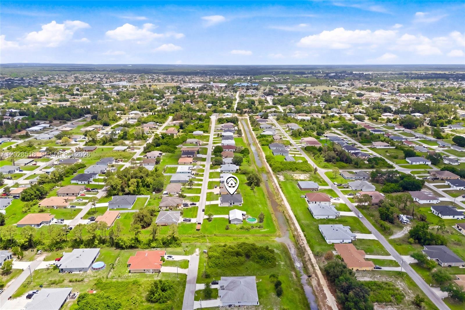 An aerial view shows a residential neighborhood with single-family homes and a central canal — 225/227 Hightower AVE S, Lehigh Acres FL 33973, LEHIGH ACRES, FL