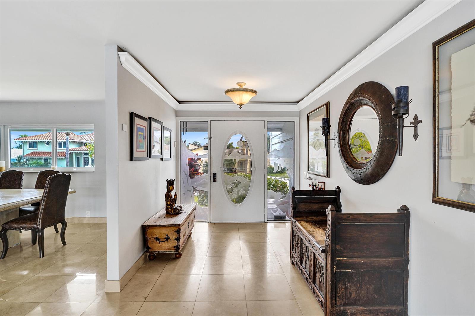 An entryway features tile floors, a wooden bench, a round mirror, and a front door — 3001 NE 47th Street, Lighthouse Point FL 33064, LIGHTHOUSE POINT, FL