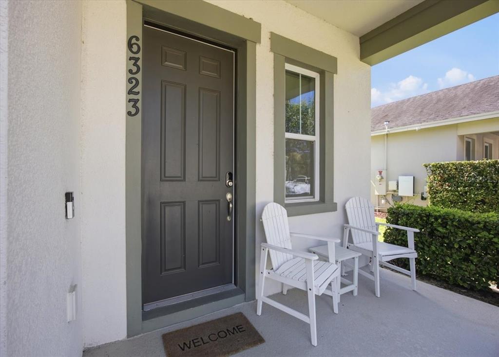 A front porch features a dark door, two white chairs, and a welcome mat — 6323 HAMLIN RESERVE BOULEVARD, WINTER GARDEN, FL