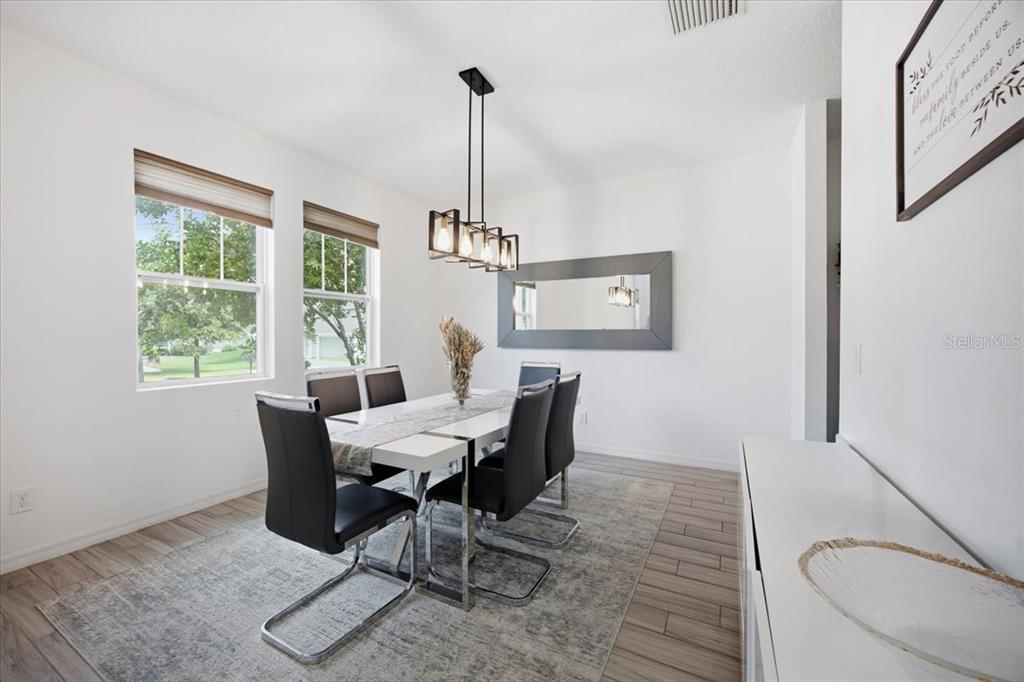 A dining room features a white table, six black chairs, a chandelier, and a mirror — 6323 HAMLIN RESERVE BOULEVARD, WINTER GARDEN, FL