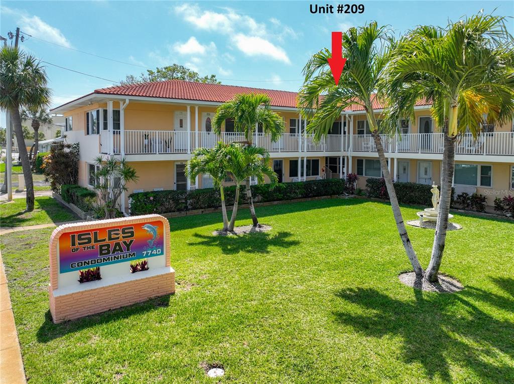 The exterior of a two-story condominium building with a lawn and palm trees — 7740 BOCA CIEGA DRIVE UNIT 209, ST PETE BEACH, FL