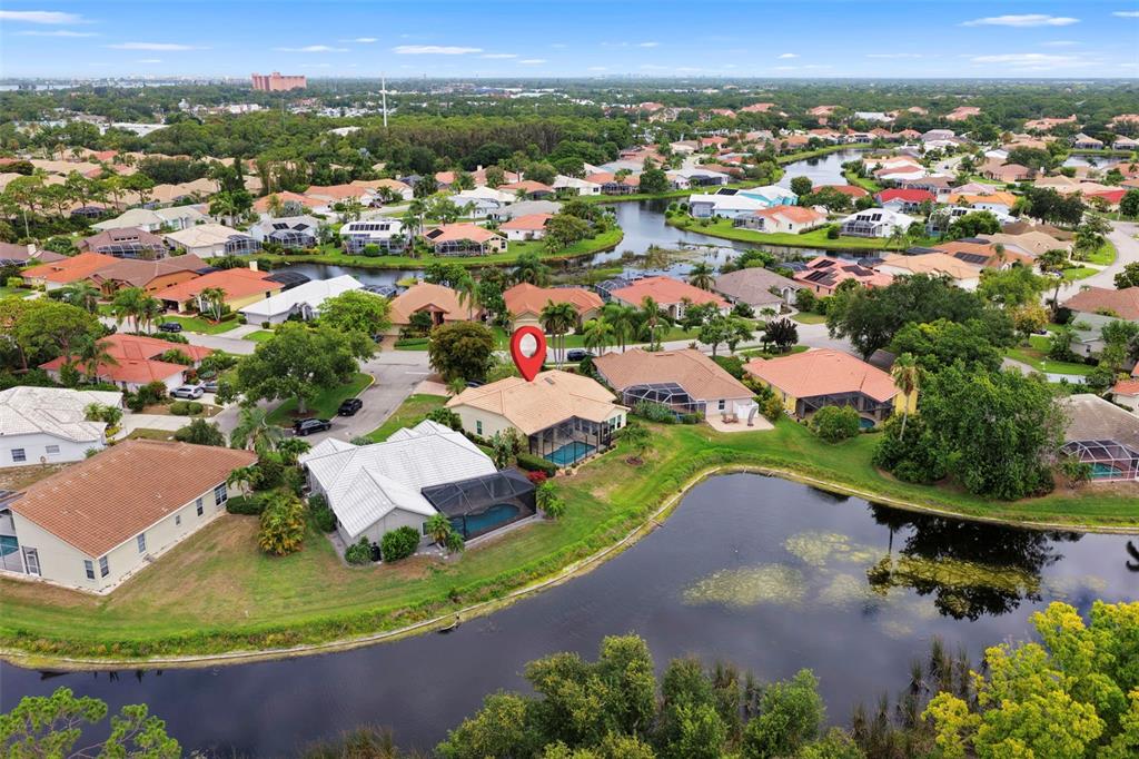 An aerial view of a suburban neighborhood featuring houses with pools and a large pond — 4174 HEARTHSTONE DRIVE, SARASOTA, FL
