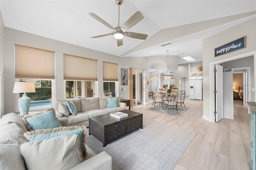 A living room with light wood floors, a ceiling fan, and a view of a pool — 4174 HEARTHSTONE DRIVE, SARASOTA, FL