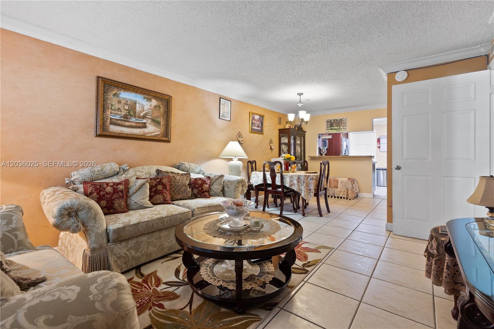 A living room and dining area feature tile flooring, textured ceilings, and warm-toned walls — 3777 NW 78th Ave # 9C, Davie FL 33024, DAVIE, FL