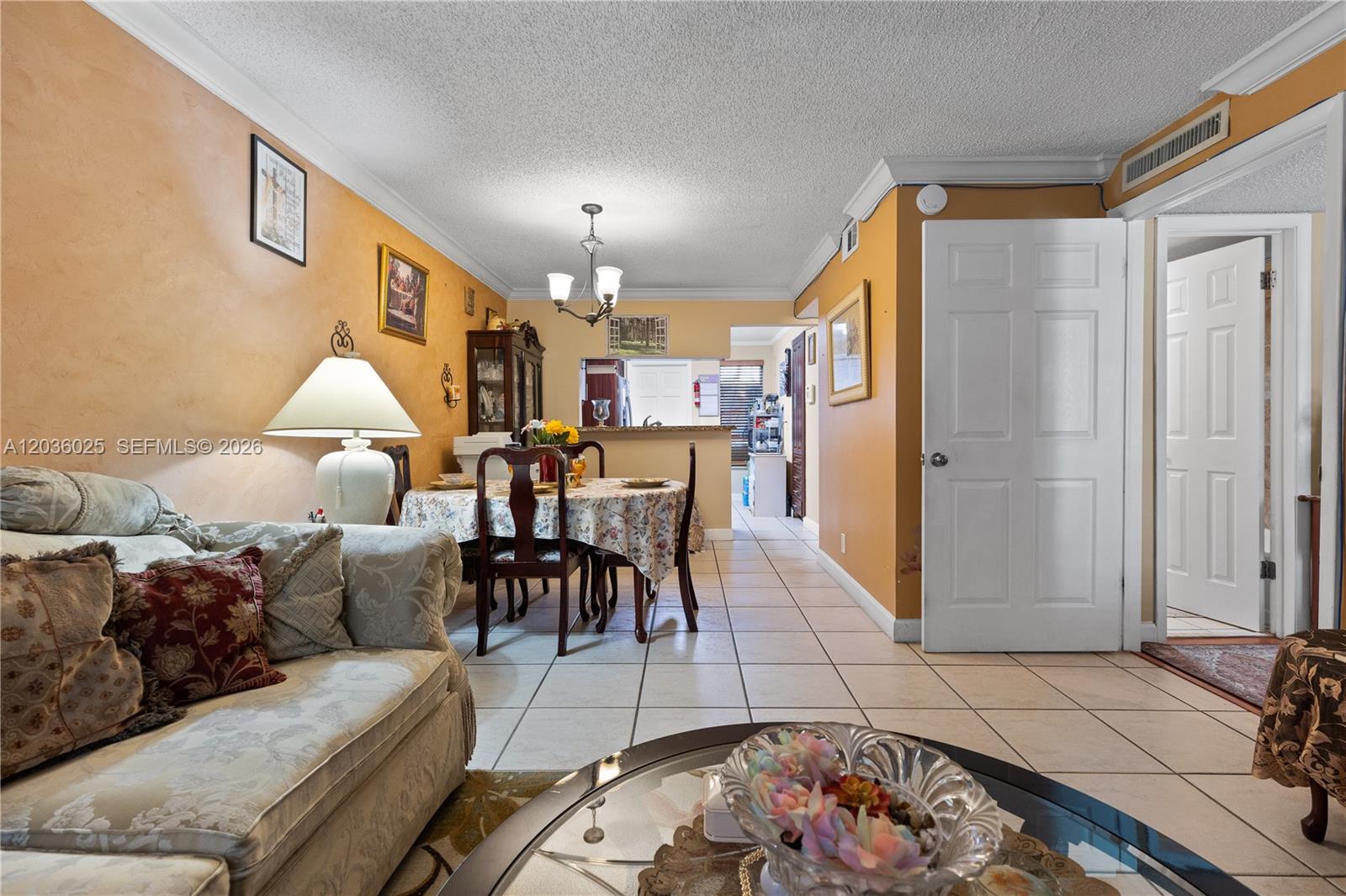A living and dining area features tile flooring, orange walls, and a floral tablecloth — 3777 NW 78th Ave # 9C, Davie FL 33024, DAVIE, FL