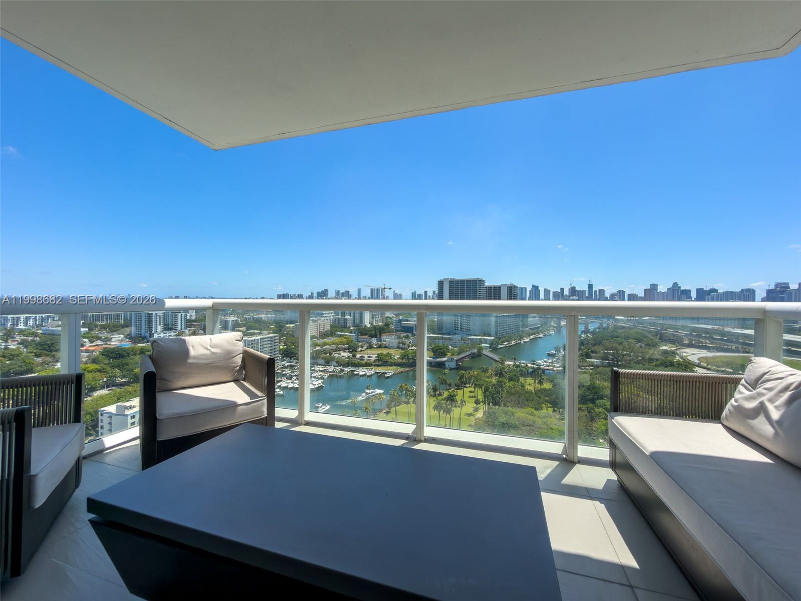 A balcony with outdoor furniture overlooks a city skyline, a waterway, and green space — 1861 NW S River Dr # 2308, Miami FL 33125, MIAMI, FL