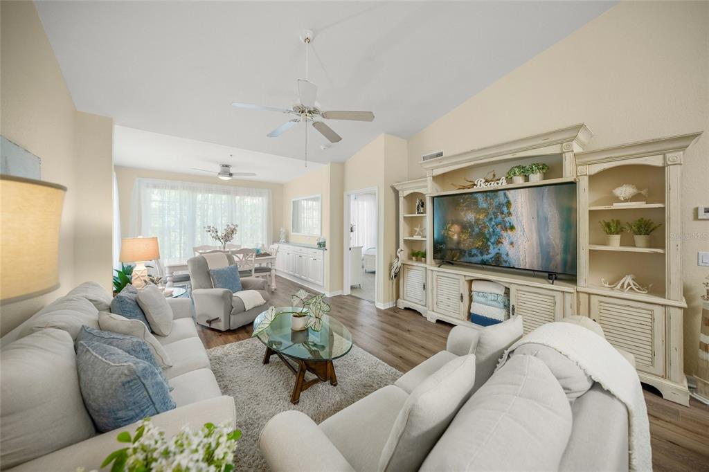 A living room features a large entertainment center, a white sofa, and a glass coffee table — 4166 CENTRAL SARASOTA PARKWAY UNIT 533, SARASOTA, FL
