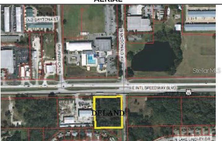 This is an aerial map showing a vacant rectangular lot highlighted in yellow near a highway — E INTERNATIONAL SPEEDWAY AVENUE, DELAND, FL