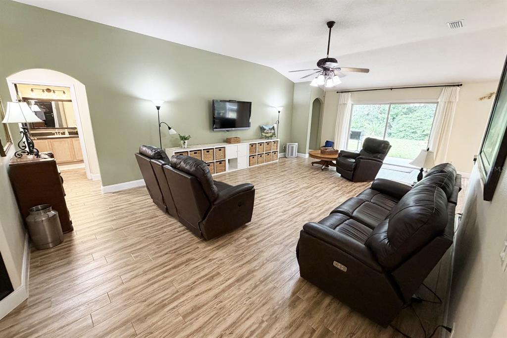 A living room with wood-look tile floors, leather furniture, and a wall-mounted television — 1 SLEEPING BEAUTY PLACE, PALM COAST, FL