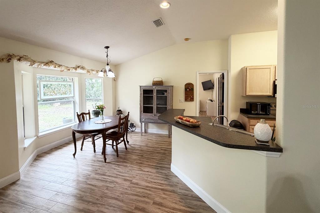 A dining area with wood-look tile floors sits adjacent to a kitchen with a breakfast bar — 1 SLEEPING BEAUTY PLACE, PALM COAST, FL