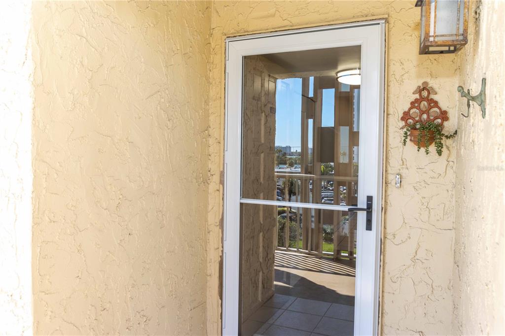 A white storm door is installed in a textured beige exterior wall — 105 ISLAND WAY UNIT 142, CLEARWATER BEACH, FL