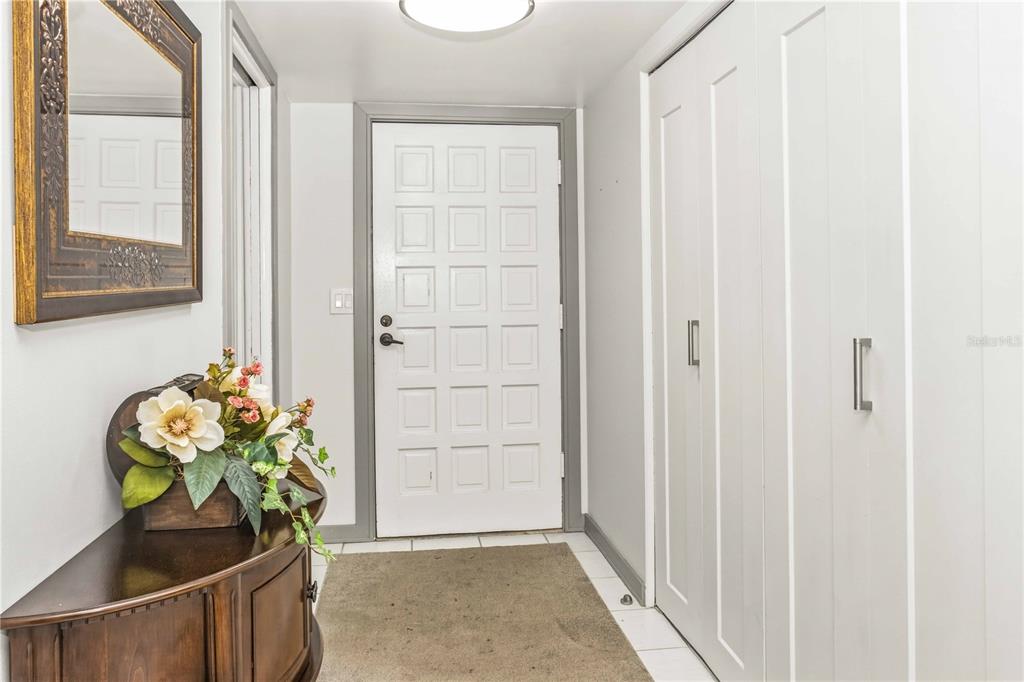 An entryway features a white front door, a wood console table, and a large closet — 105 ISLAND WAY UNIT 142, CLEARWATER BEACH, FL