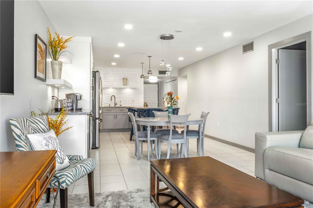 An open-concept living and dining area features tile flooring, a kitchen, and modern lighting — 105 ISLAND WAY UNIT 142, CLEARWATER BEACH, FL