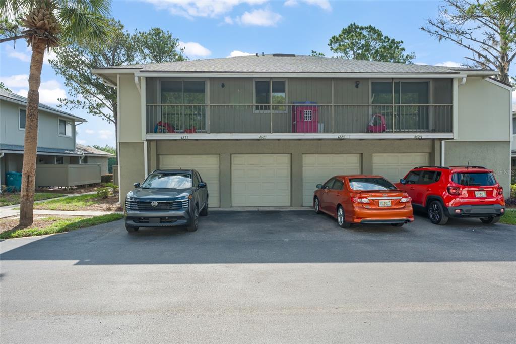 A two-story building features a screened balcony above three garage doors and parked cars — 4623 RING NECK ROAD UNIT B-1, ORLANDO, FL