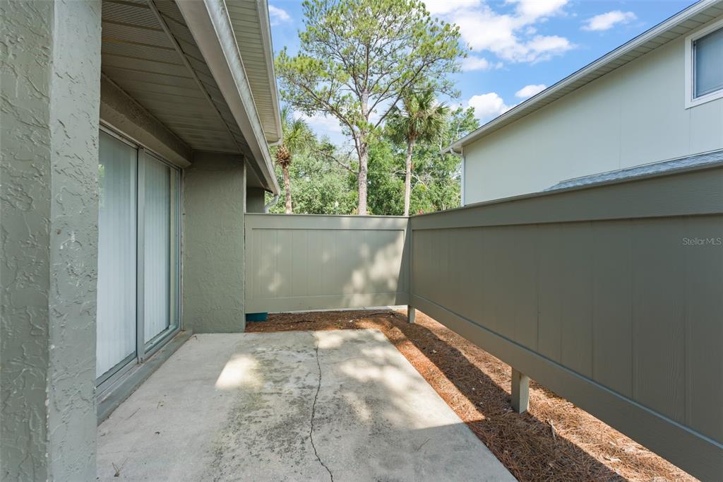 A concrete patio is enclosed by a privacy fence next to a house exterior — 4623 RING NECK ROAD UNIT B-1, ORLANDO, FL