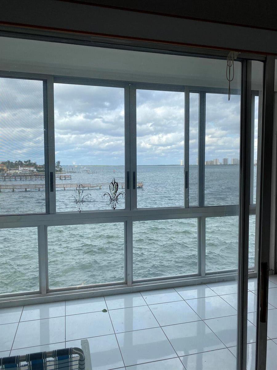 A tiled room features large sliding glass windows with a direct view of the ocean — 410 Wilma Circle, Riviera Beach FL 33404, RIVIERA BEACH, FL