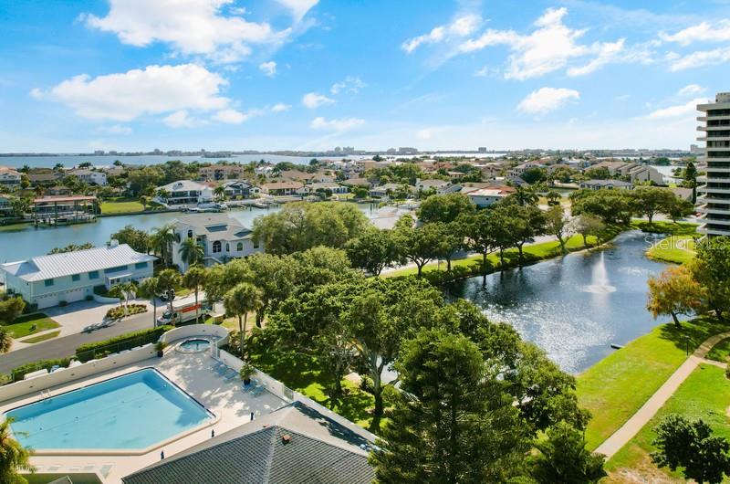 An elevated view shows a swimming pool, a pond with a fountain, and surrounding residential homes — 5940 PELICAN BAY PLAZA S UNIT 1105, GULFPORT, FL