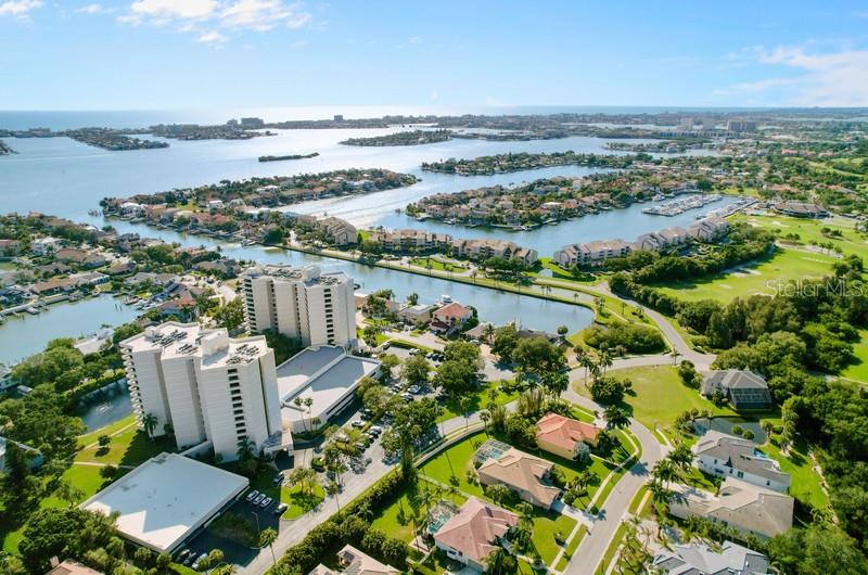 An aerial view shows high-rise condominiums surrounded by residential homes, waterways, and coastal landscape — 5940 PELICAN BAY PLAZA S UNIT 1105, GULFPORT, FL