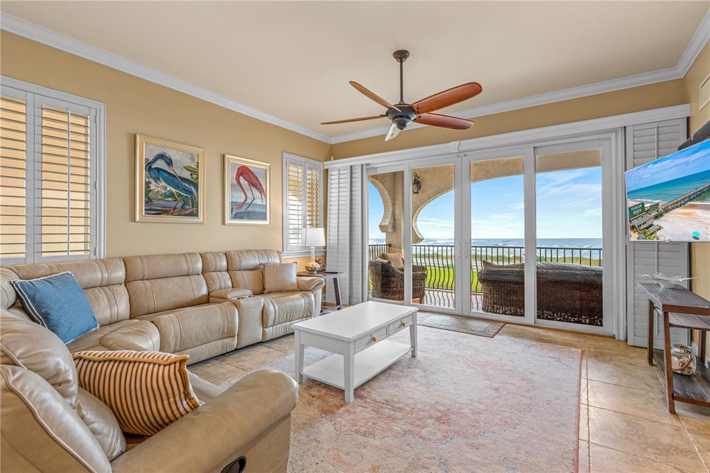 A living room with a beige leather sectional, white coffee table, and oceanfront balcony access — 2450 N OCEAN SHORE BOULEVARD UNIT 211, FLAGLER BEACH, FL