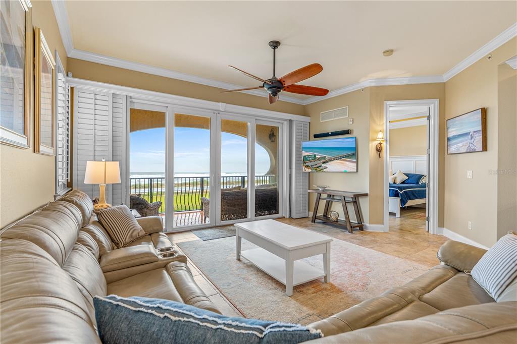 A living room features a leather sofa, a white coffee table, and sliding glass balcony doors — 2450 N OCEAN SHORE BOULEVARD UNIT 211, FLAGLER BEACH, FL