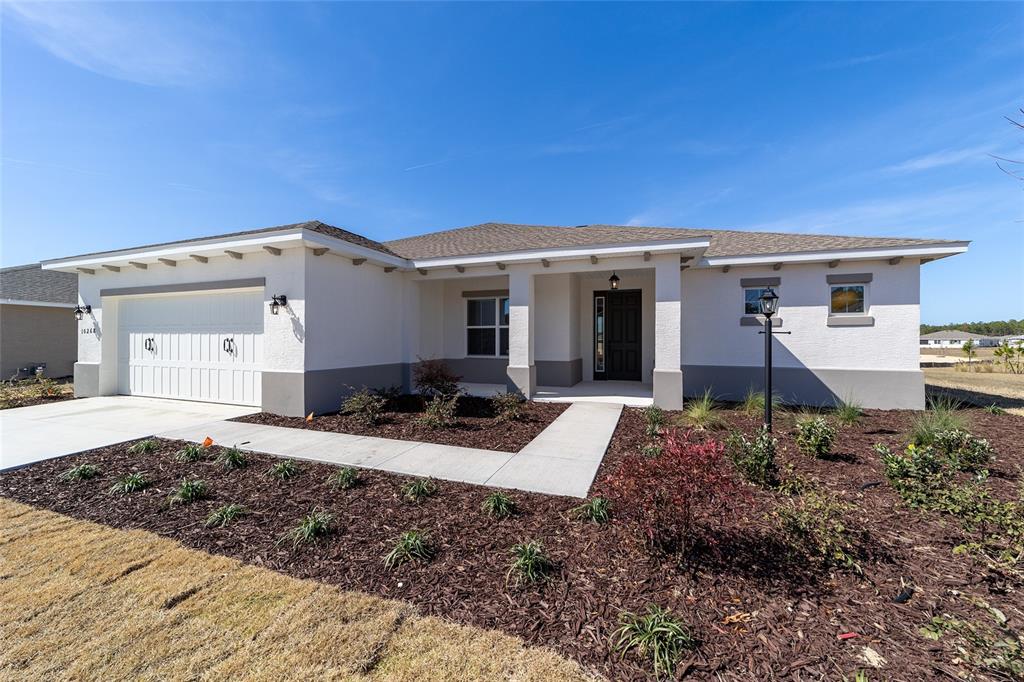 A single-story house with a white stucco exterior, a two-car garage, and a landscaped yard — 10268 SW 105TH TERRACE, OCALA, FL