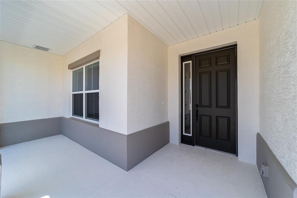 A covered front porch features a dark brown door with a sidelight and stucco walls — 10268 SW 105TH TERRACE, OCALA, FL