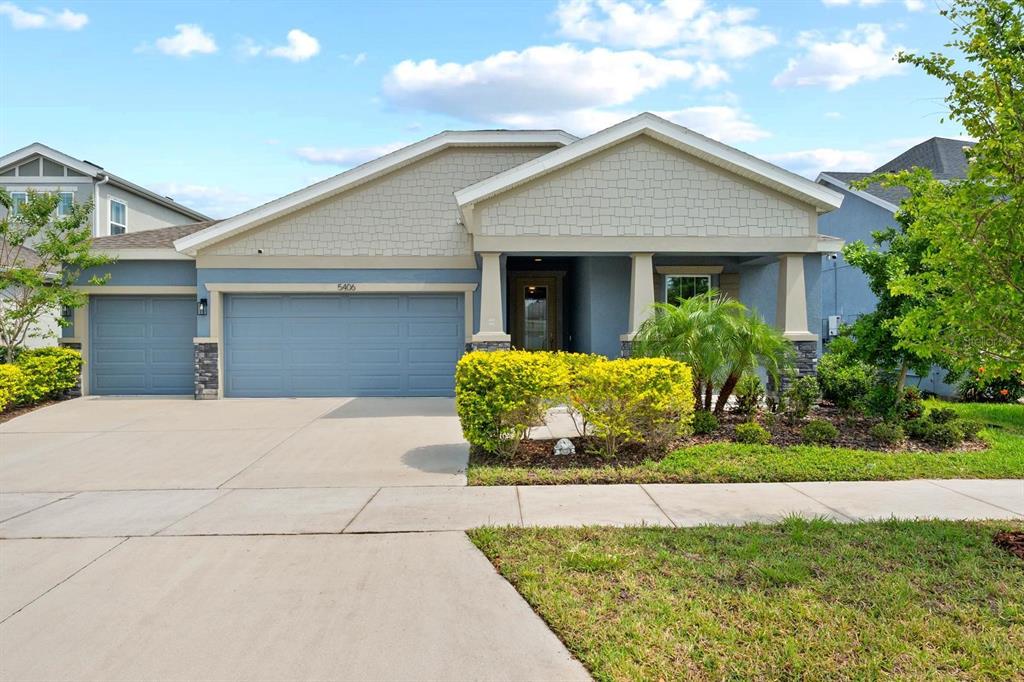 A blue single-story house with a two-car garage, stone accents, and a covered front porch — 5406 LIMELIGHT DRIVE, APOLLO BEACH, FL