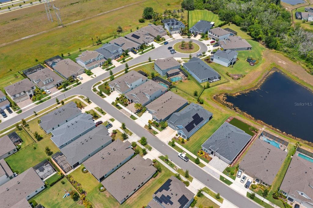 An aerial view shows a suburban neighborhood with houses, streets, and a retention pond — 5406 LIMELIGHT DRIVE, APOLLO BEACH, FL