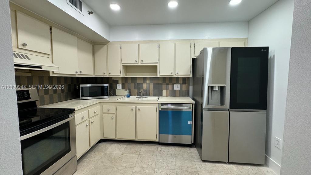 A kitchen features off-white cabinets, stainless steel appliances, and a tiled backsplash — 919 Hillcrest Dr # 201, Hollywood FL 33021, HOLLYWOOD, FL