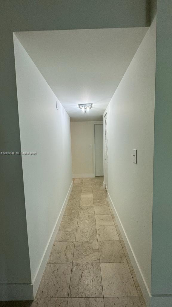 A narrow hallway features light-colored tile flooring and white walls leading toward a closed door — 919 Hillcrest Dr # 201, Hollywood FL 33021, HOLLYWOOD, FL