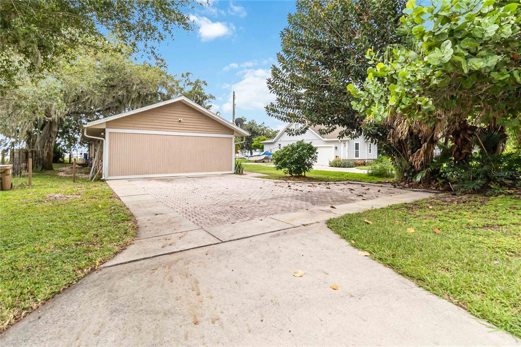 A detached garage with a paved driveway sits on a grassy lot with trees — 6210 ALLIGATOR LAKE SHORE E, ST CLOUD, FL