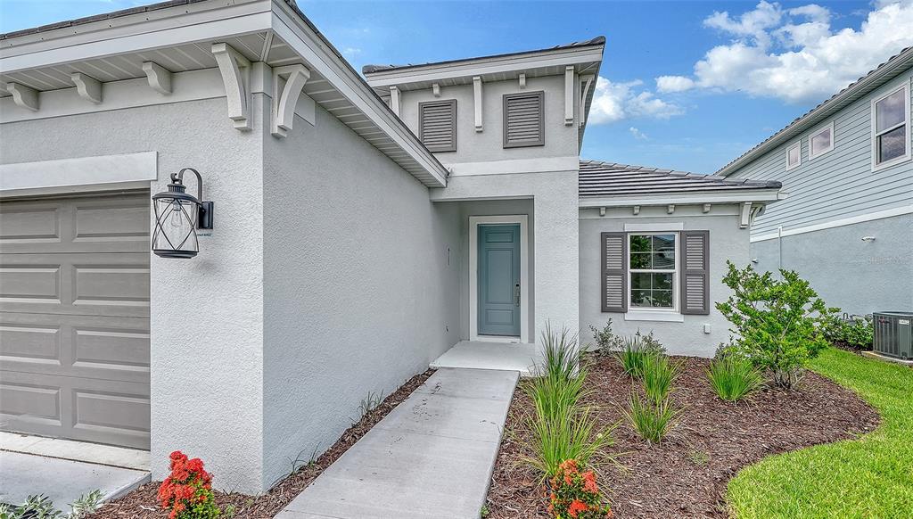 The exterior of a light gray house features a blue front door and garage — 6563 BIG BAYOU DRIVE, SARASOTA, FL