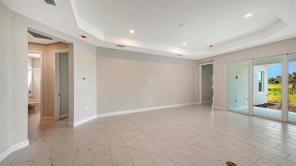 An empty room with light-colored tile flooring, recessed lighting, and sliding glass doors to outdoors — 6563 BIG BAYOU DRIVE, SARASOTA, FL