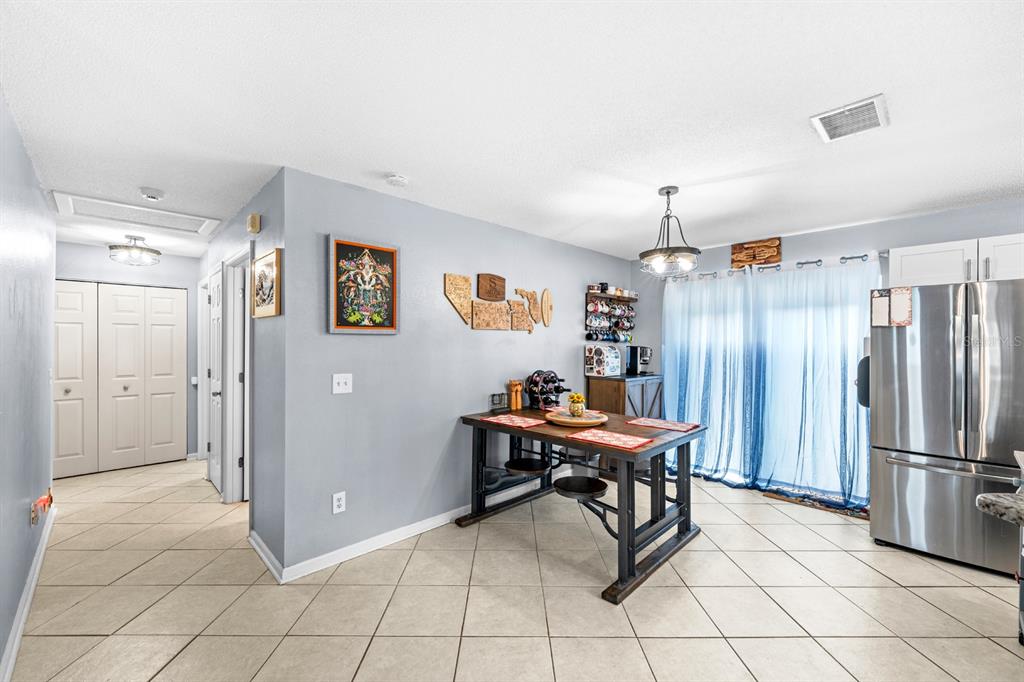 A dining area features a wooden table, tile flooring, light blue walls, and a stainless refrigerator — 5316 W IDAHO STREET, TAMPA, FL