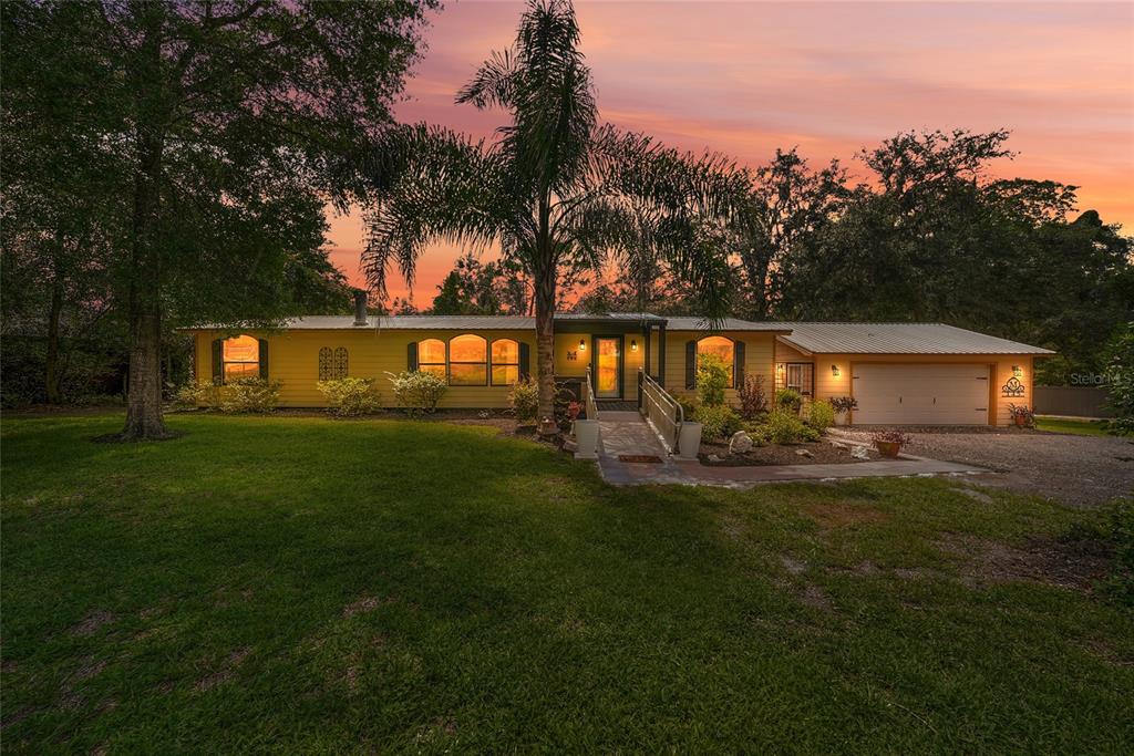 A yellow single-story house with a metal roof, a palm tree, and a wheelchair ramp — 145 CRYSTAL LAKE DRIVE, MELROSE, FL