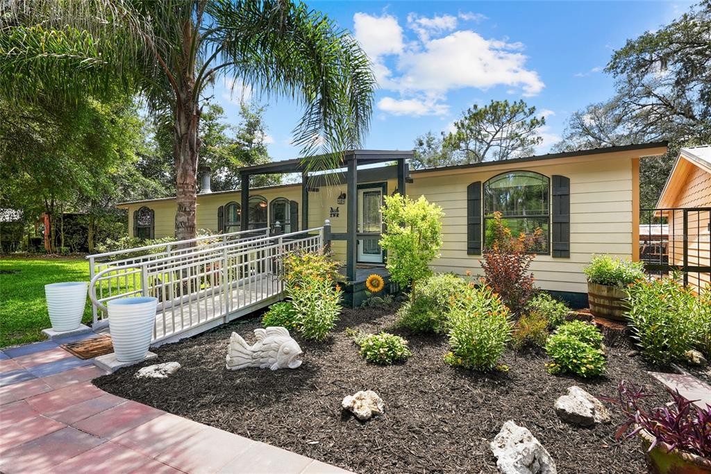 A single-story house with a wheelchair ramp leading to the front entrance and landscaped yard — 145 CRYSTAL LAKE DRIVE, MELROSE, FL