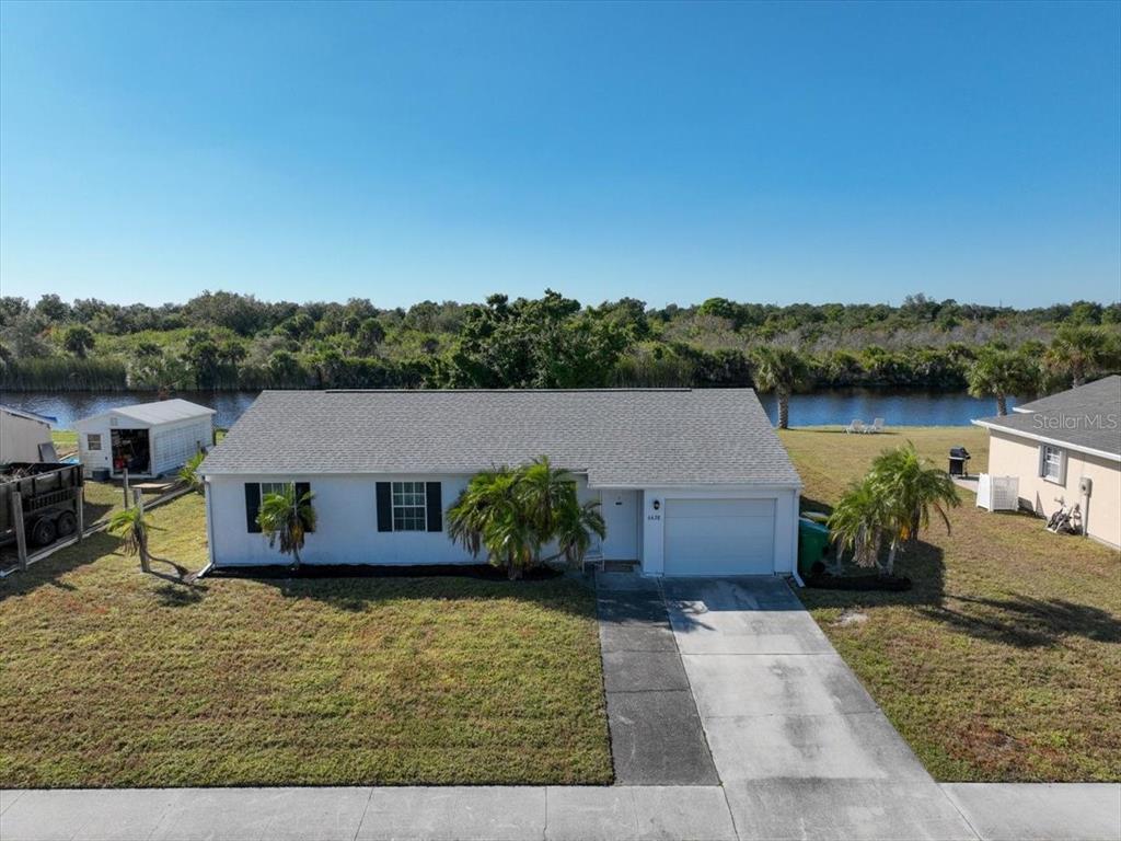 An aerial view shows a single-story white house with a gray roof and attached garage — 6628 THORMAN ROAD, PORT CHARLOTTE, FL